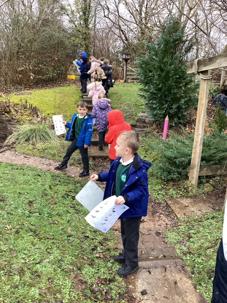 Lots of Exwick Heights Pupils outside holding a bird watch survey and looking for birds. 