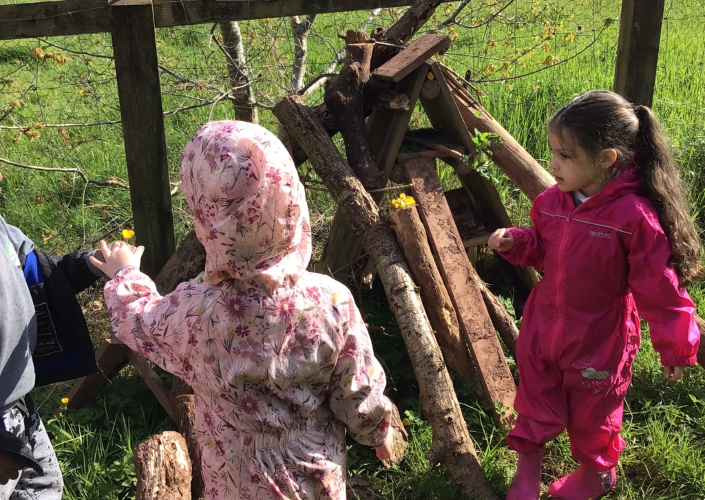 Cranbrook Education Campus pupils at Forest School stood outside next to a pile of logs