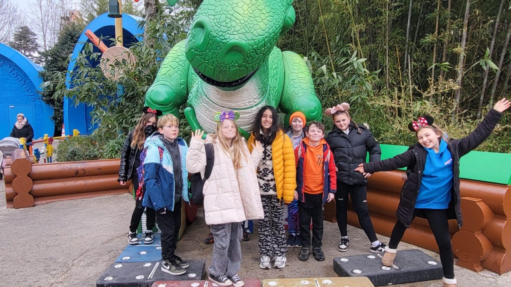 Marine Academy Primary Pupils stood with a giant dinosaur behind them 