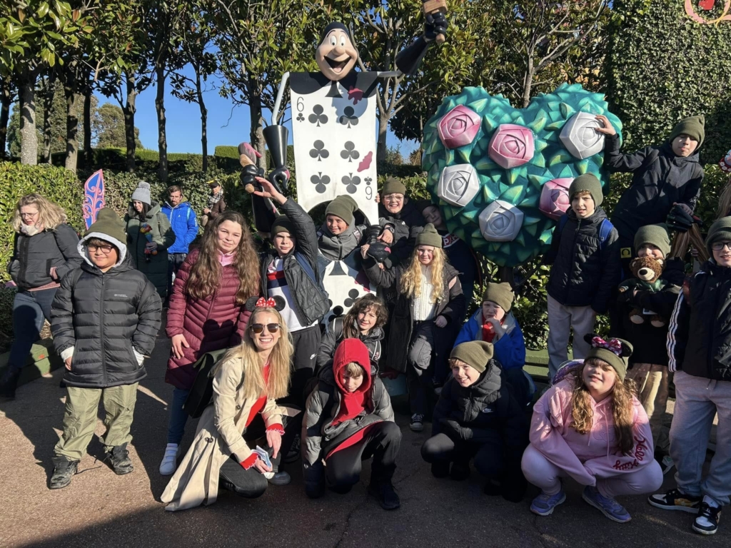 Exwick Heights Primary School stood in Disney Land Paris, with a playing card in the background. 