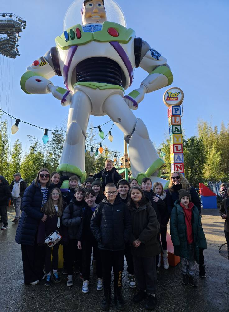 Exwick Heights Primary School stood in Disney Land Paris, with a giant statue of Buzz lightyear behind them. 