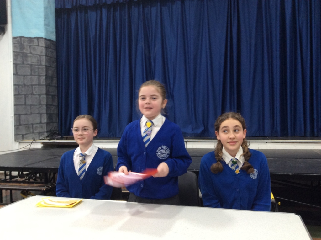 Students from Honiton Community College Hosting Youth Speak Competition 3 students behind a table.