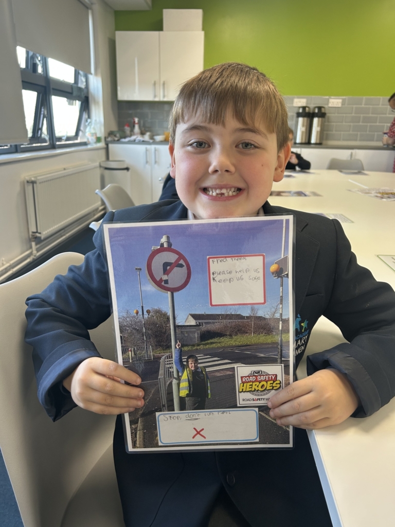 Marine Academy Primary pupil sat holding road safety booklet. 