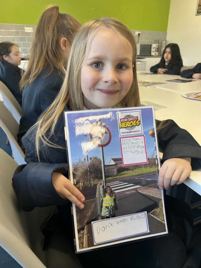 Marine Academy Primary pupil sat holding road safety booklet. 