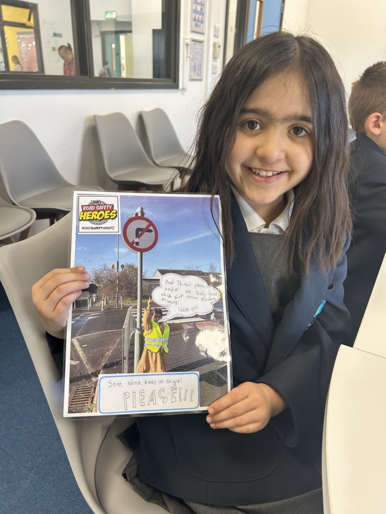 Marine Academy Primary pupil sat holding road safety booklet. 