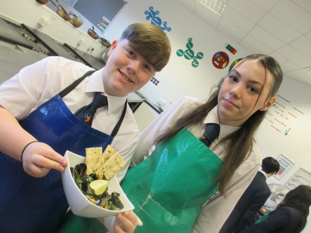 Two Marine Academy Plymouth Students holding a bowl of  Mussels 