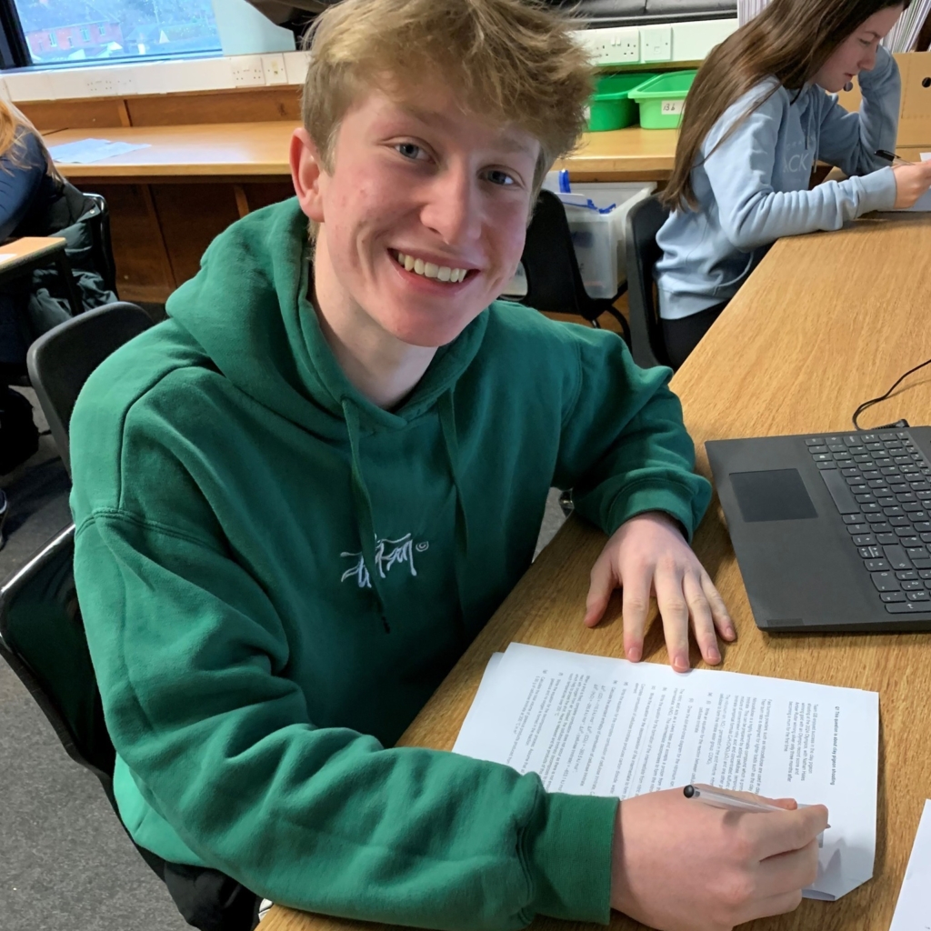 Sixth Form student from QE wearing green jumper sat a desk taking part in Chemistry Olympiad 