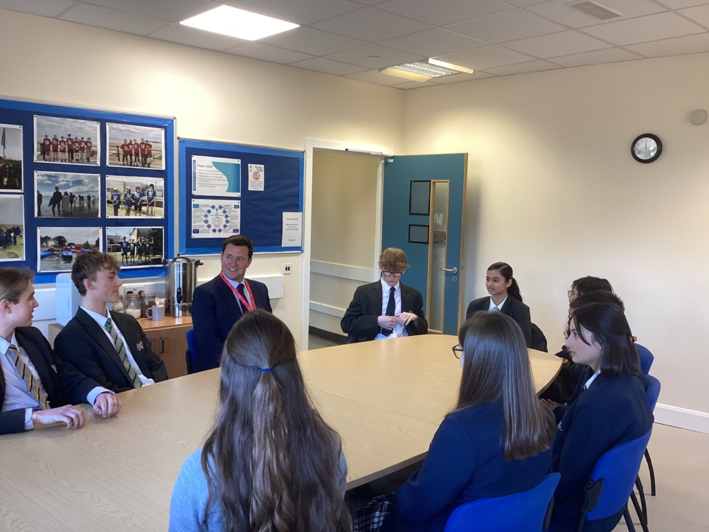 Students from Isca sat around a table speaking to Steve Race MP 