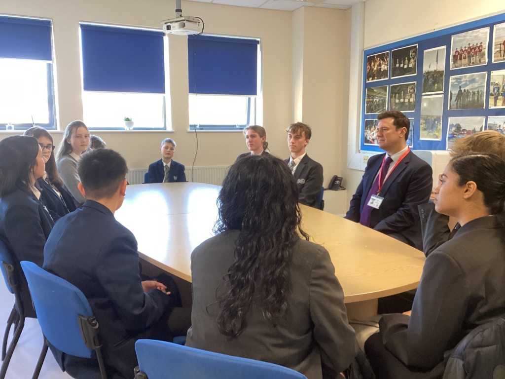 Students from Isca sat around a table speaking to Steve Race MP 