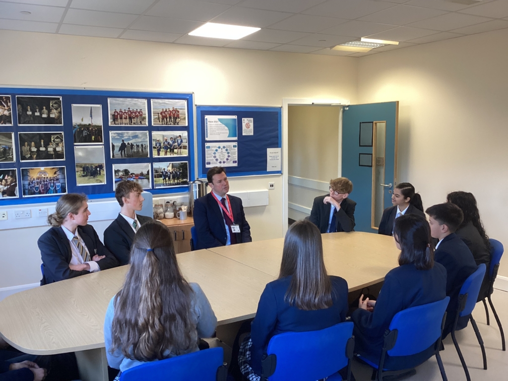 Students from Isca sat around a table speaking to Steve Race MP 