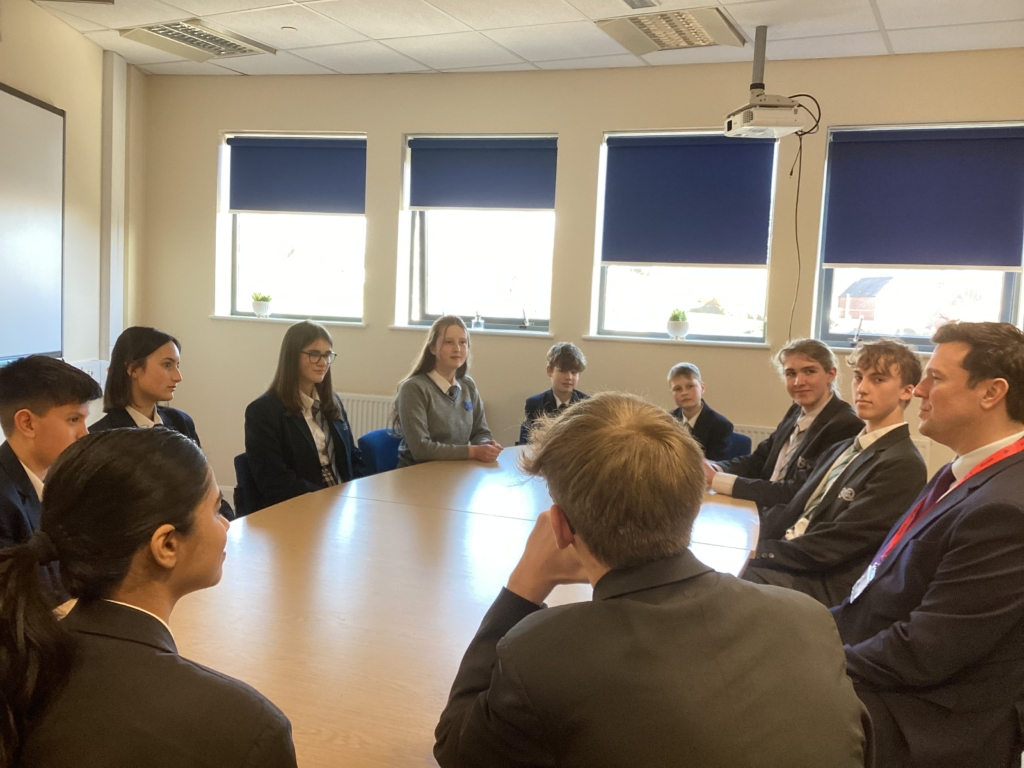 Students from Isca sat around a table speaking to Steve Race MP 