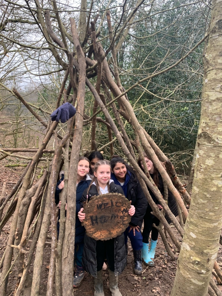 Pupils from Whipton Barton Federation inside a wigwam made of sticks. 
