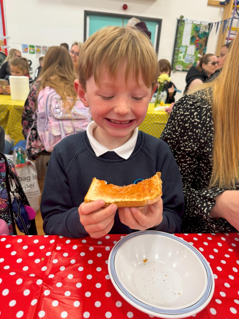 A student smiling, enjoying a piece of toast