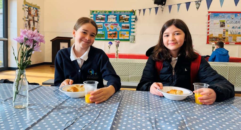 Two students smiling as they enjoy their breakfast