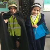 Two children dressed up in capes and bonnets