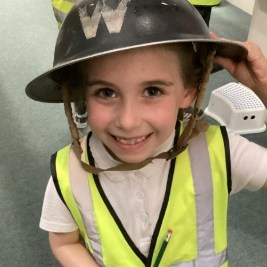 A child smiling into the camera wearing a world war two helmet
