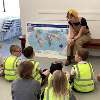 Children sat in a group listening to a teacher