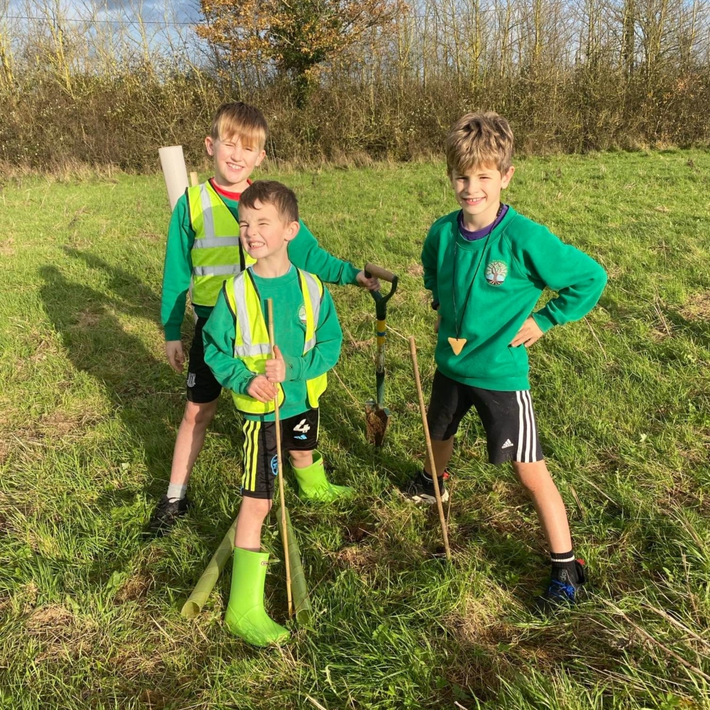 Students stood on grass with spade for planting