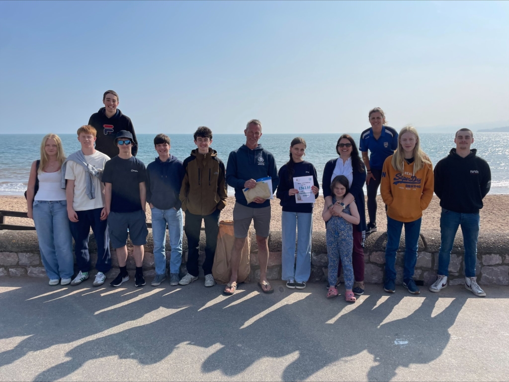 Students stood at edge of beach with blue sea behind them