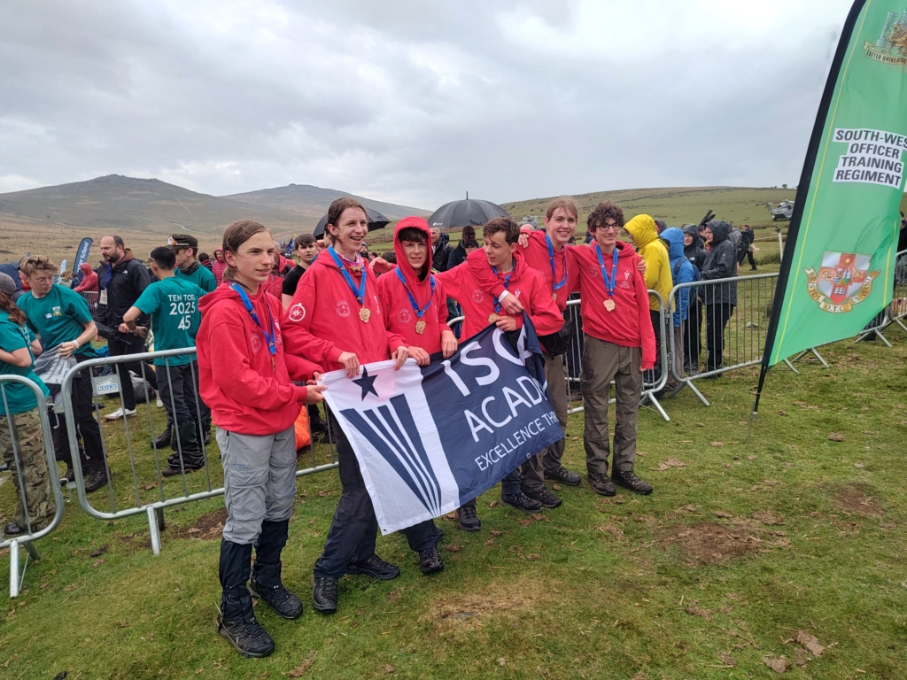 Isca Students holding an Isca flag and the end of Ten Tors