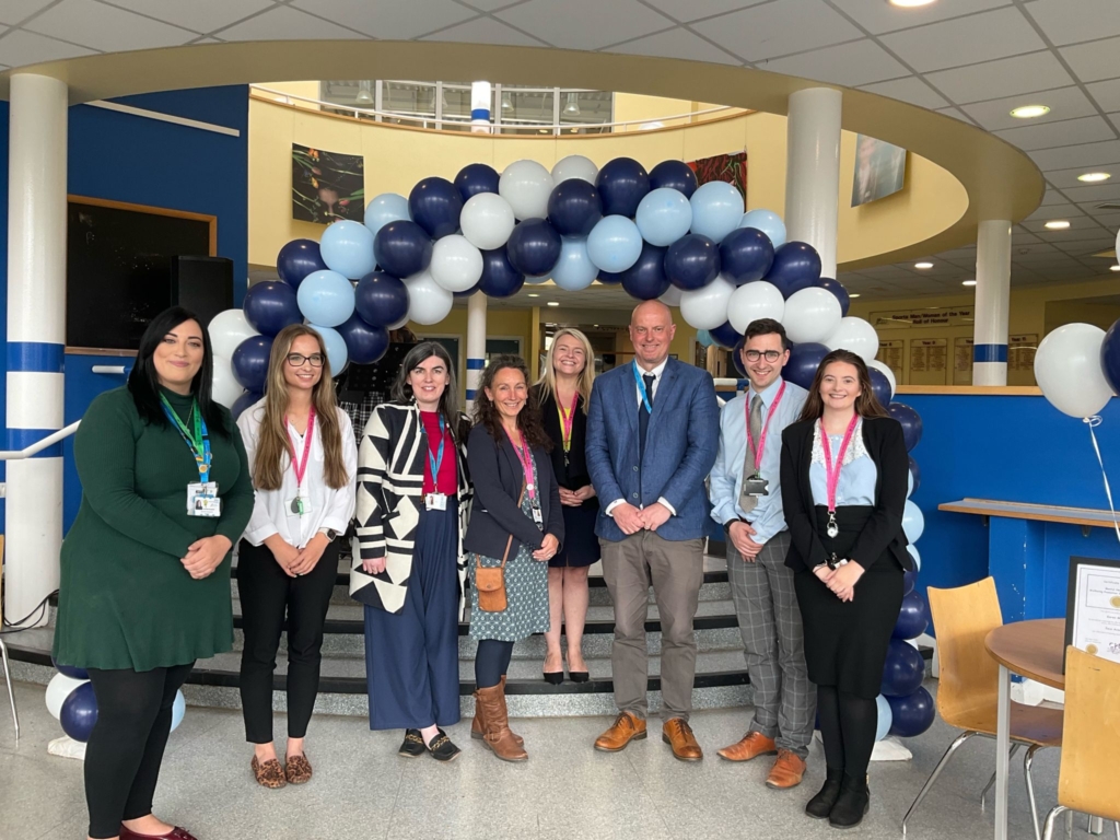 Staff members stood posing for the camera in front of a blue balloon arch