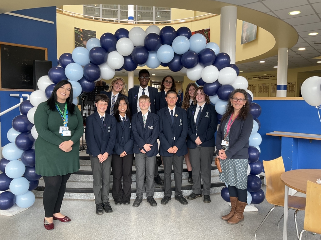 Staff and students stood in front of a blue balloon arch
