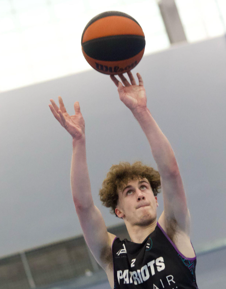 Male student reaching for basketball mid air