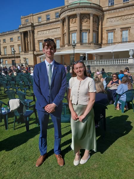 Two students stood in Buckingham Palace Garden smiling at camera