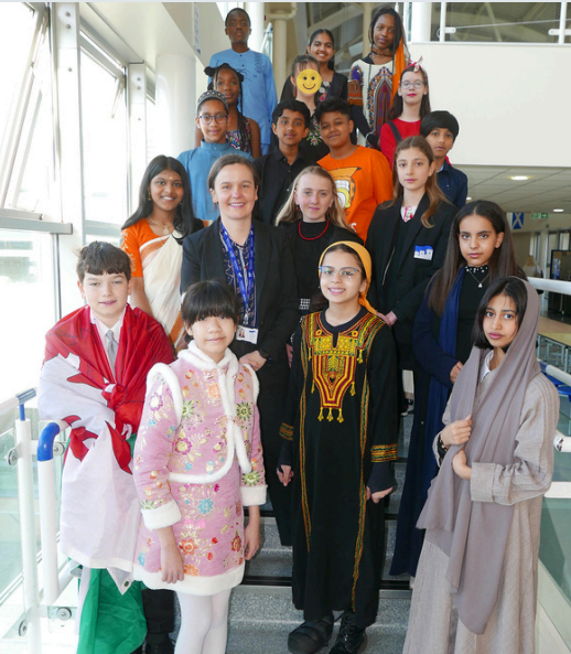 Students from St James stood on stairs wearing traditional or cultural dress