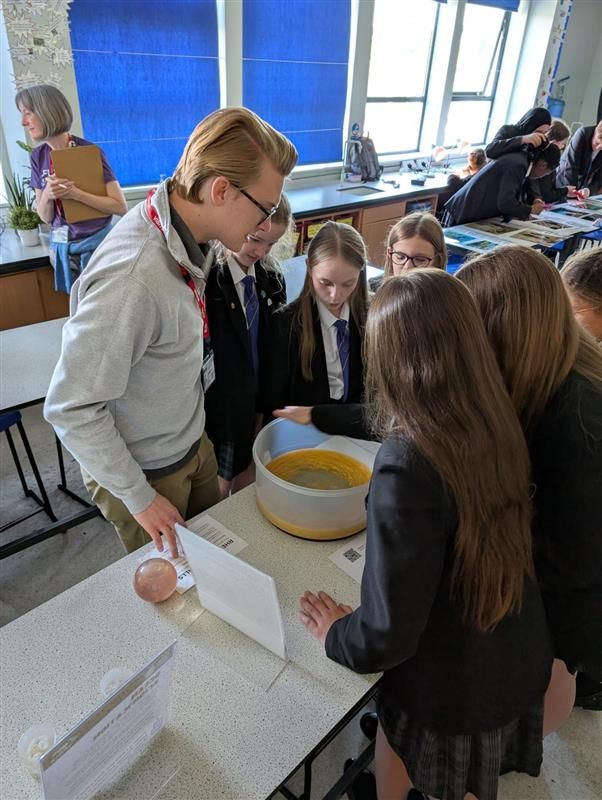 Students gathered round a table watching an experiment