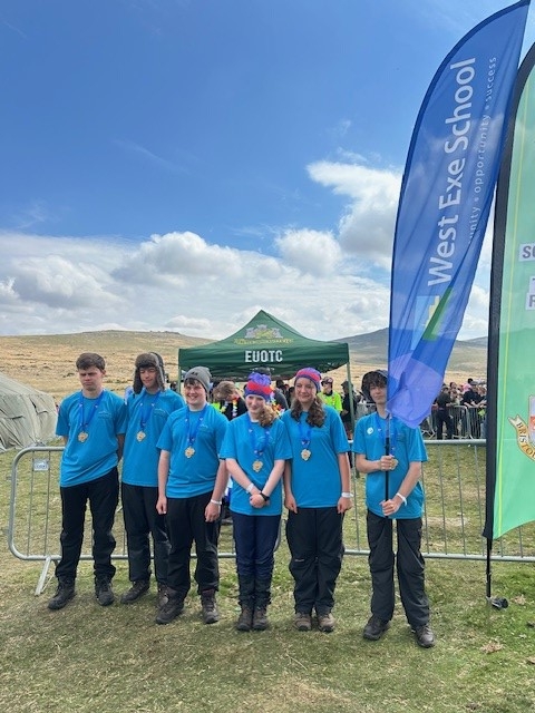 West Exe Team stood with flags either side of them at the finish of the Ten Tors