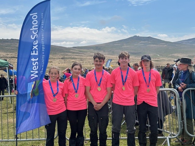 West Exe Team stood with flags either side of them at the finish of the Ten Tors