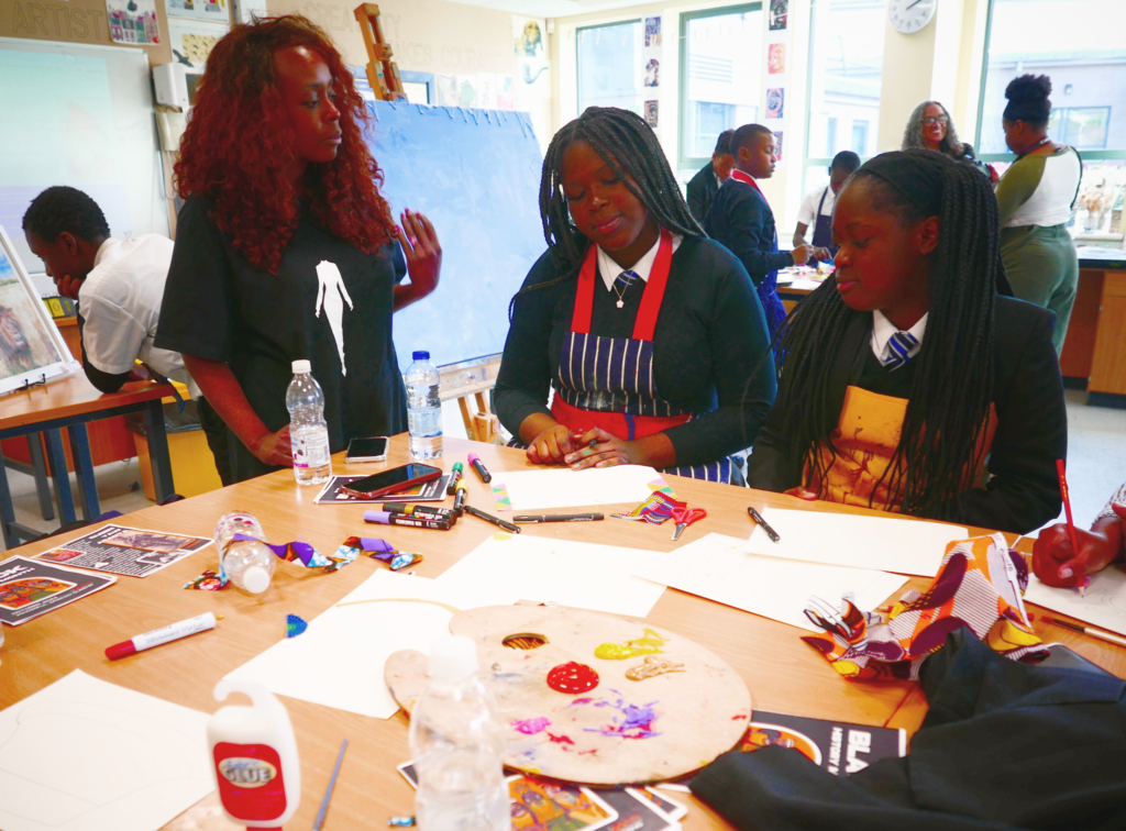 Two students sat at table with workshop leader offering guidance