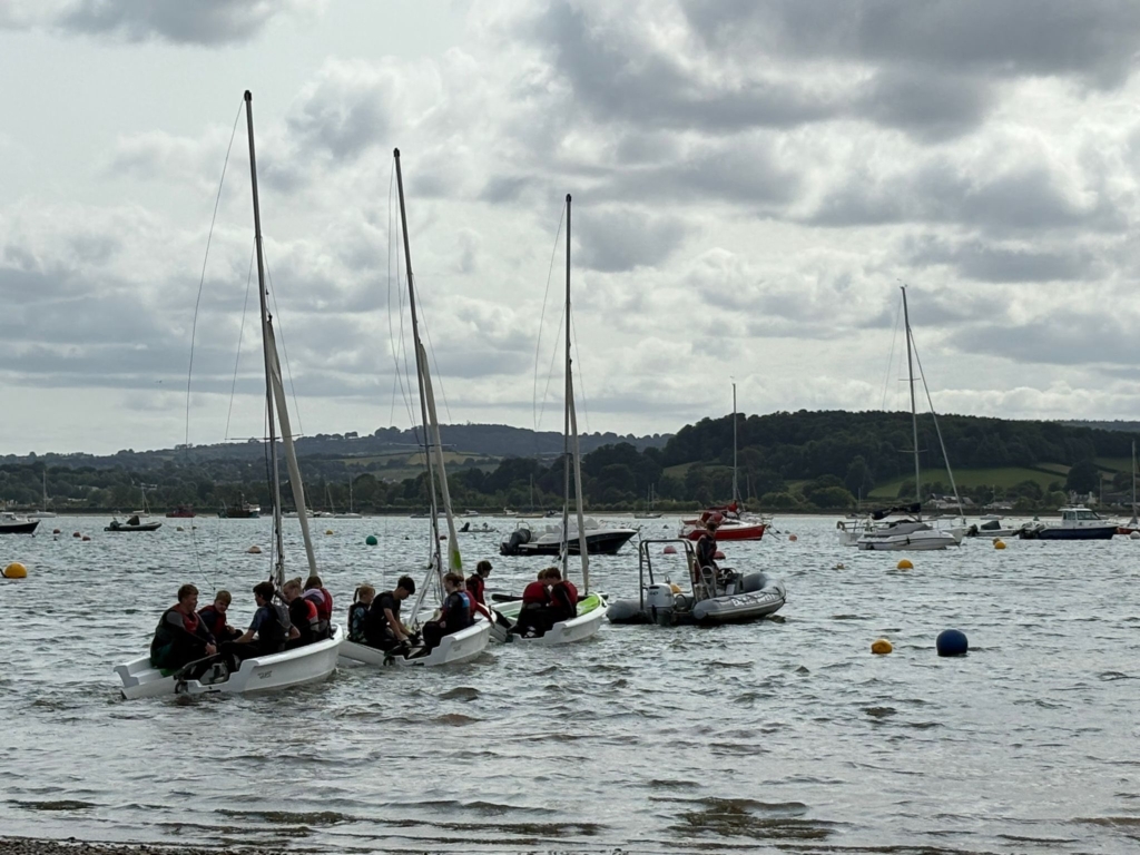 Photo of white boats on water with students