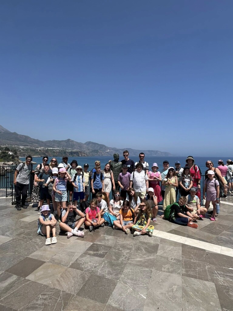 Students stood in a line on the sea front with the sea and hills in the distance