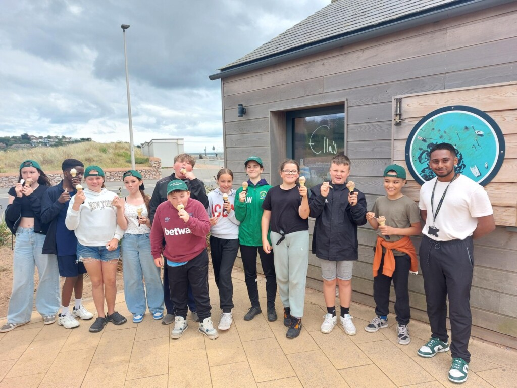 A row of students smiling at the camera holding an ice cream