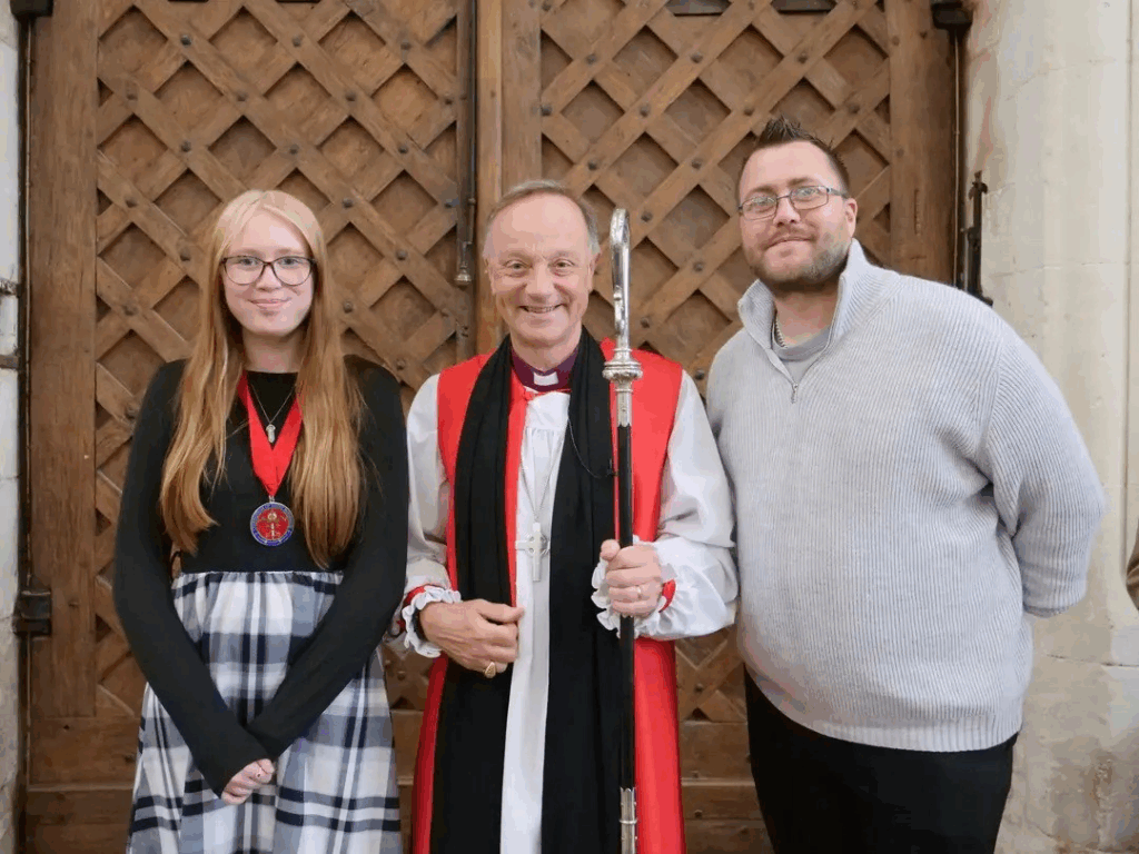 Student on the left wearing a medal around her neck stood with the bishop