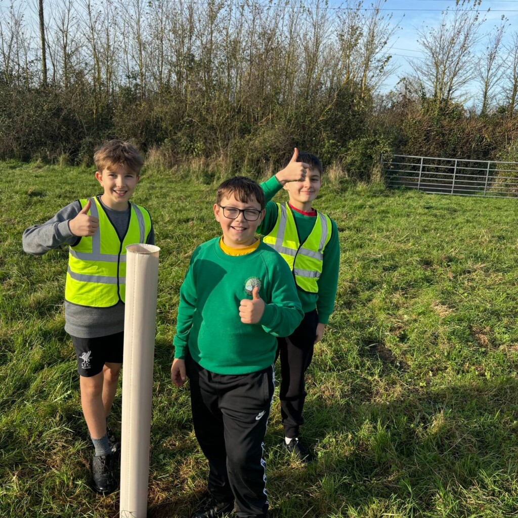 Three students exploring outside, two wearing yellow high vis jackets