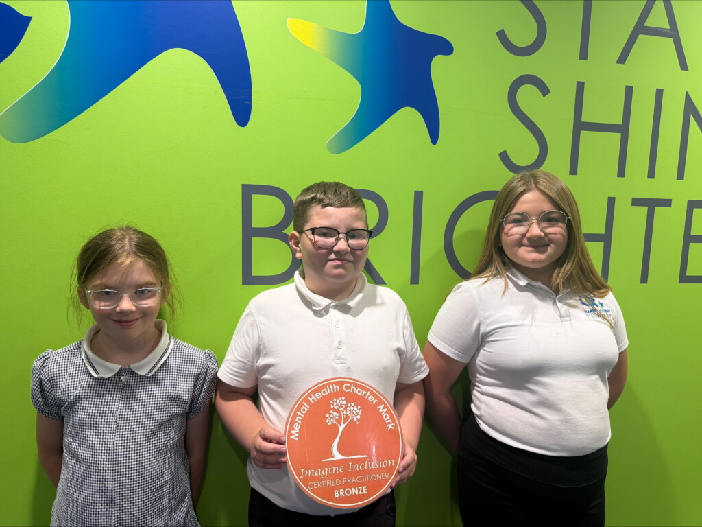 Three students stood with the mental health charter mark award