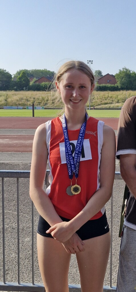 Sophia stood at running track with medals around her neck. 