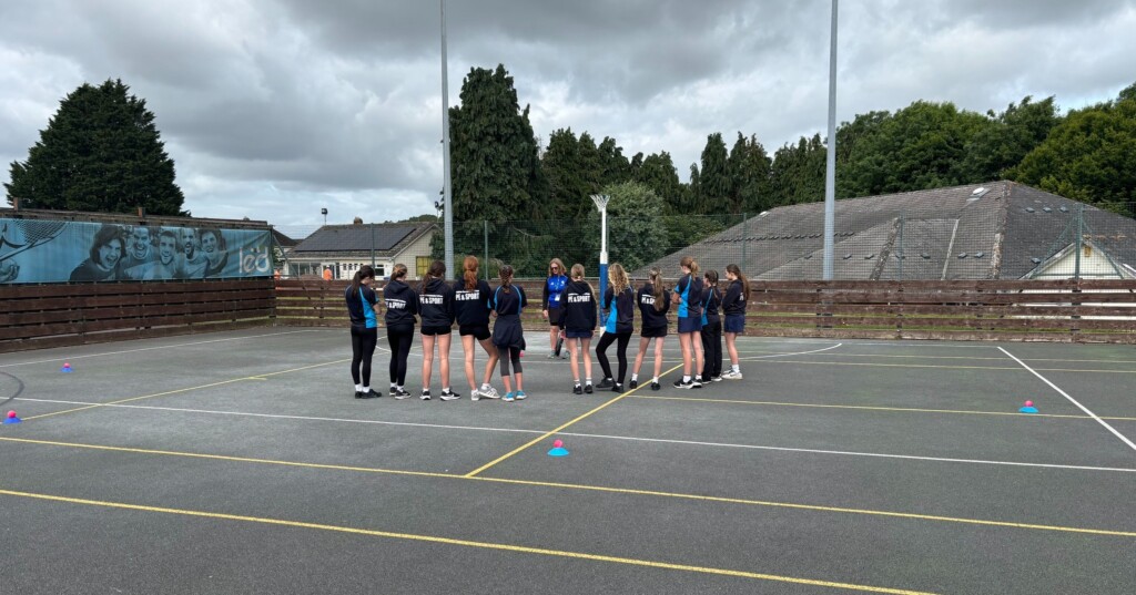Honiton girls outside on court practicing cricket drills in a circle
