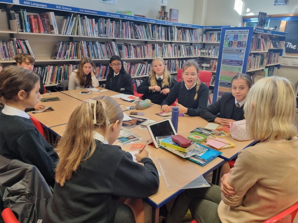 Students sat around a table in a library talking to author