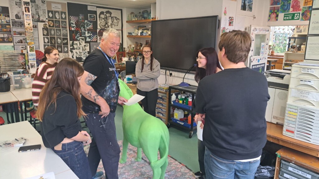 Students and staff stood around looking at green model horse