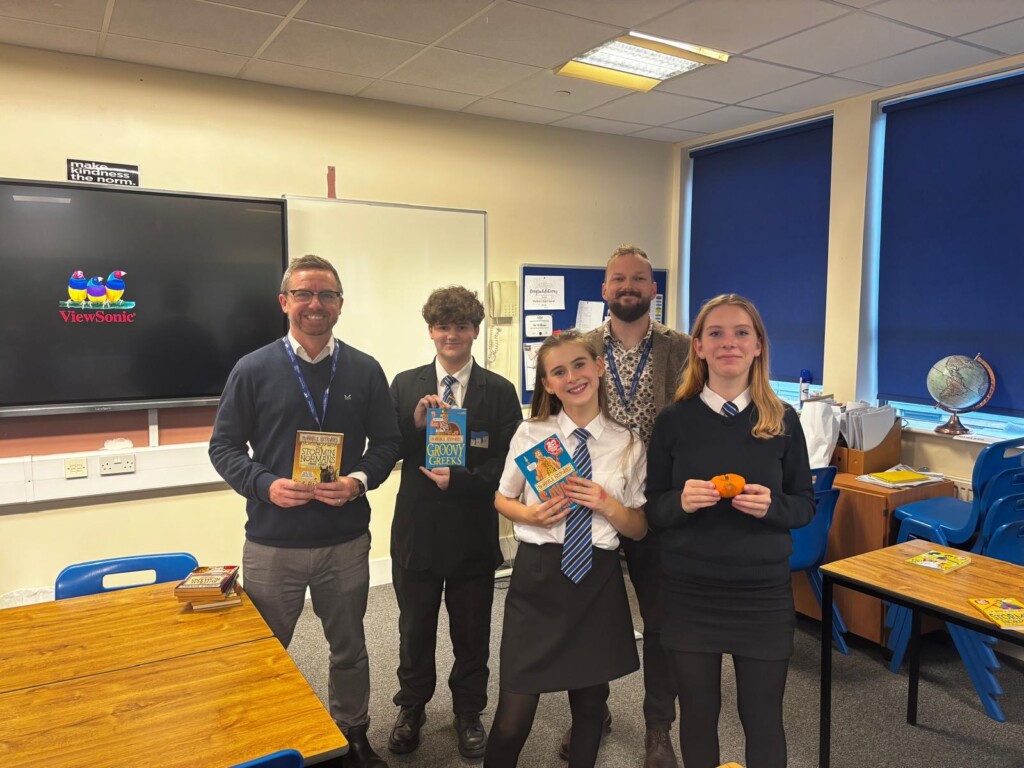 Three students and two teachers stood in a classroom holding books