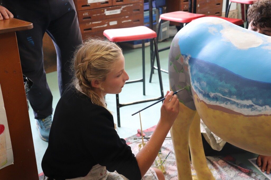 Student painting model horse in blue