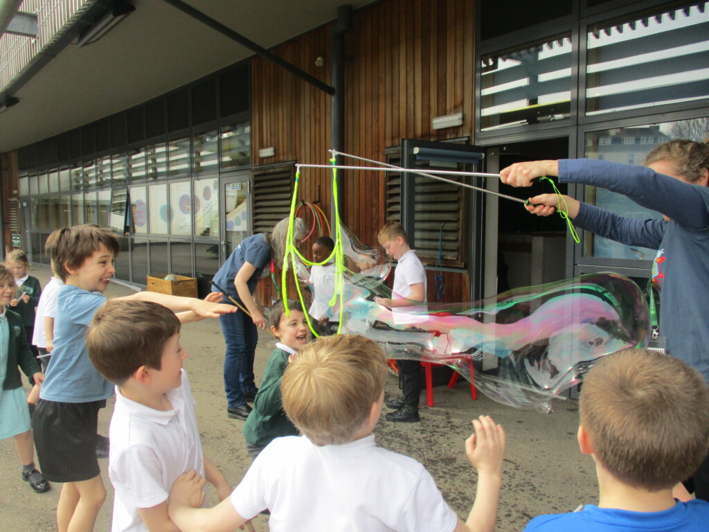 Students outdoors playing with a bubble wand