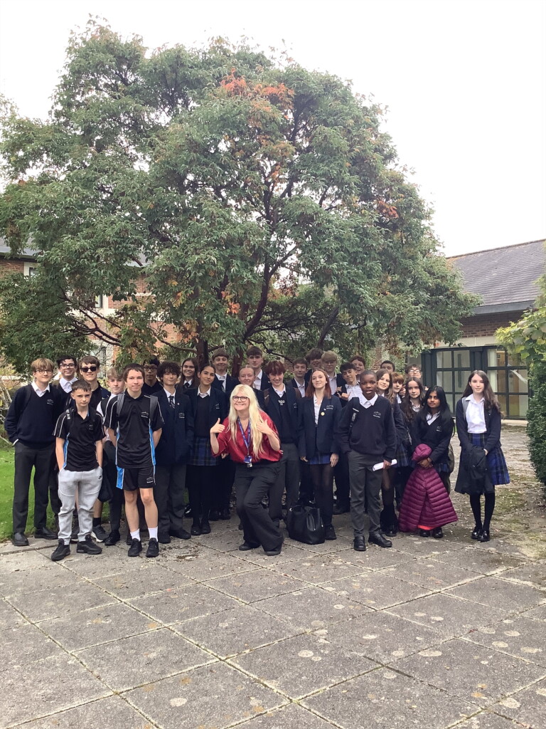 A group of students stood smiling for a picture in front of a green tree