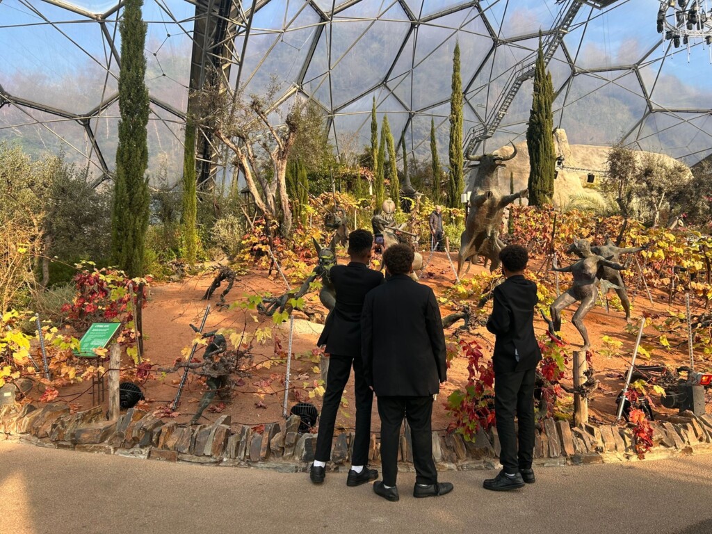 Three students in uniform examining plants