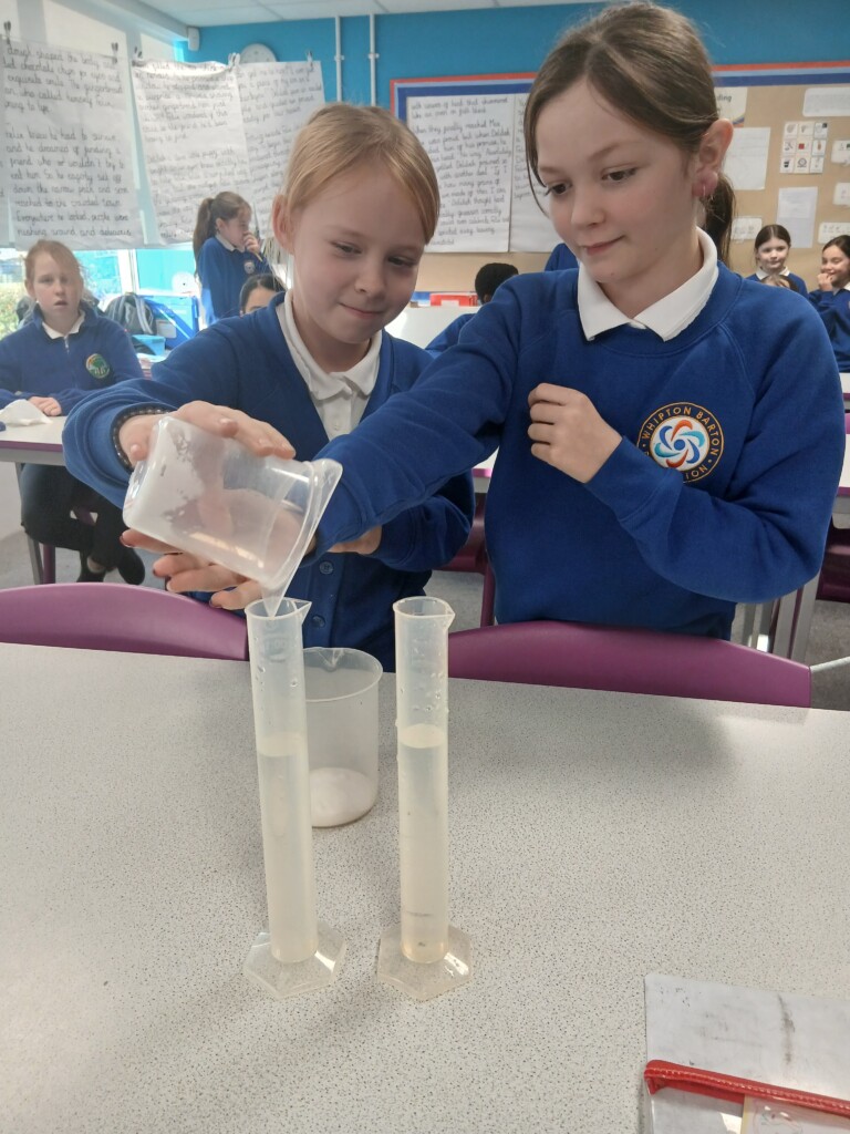 Two students pouring liquid into test tubes