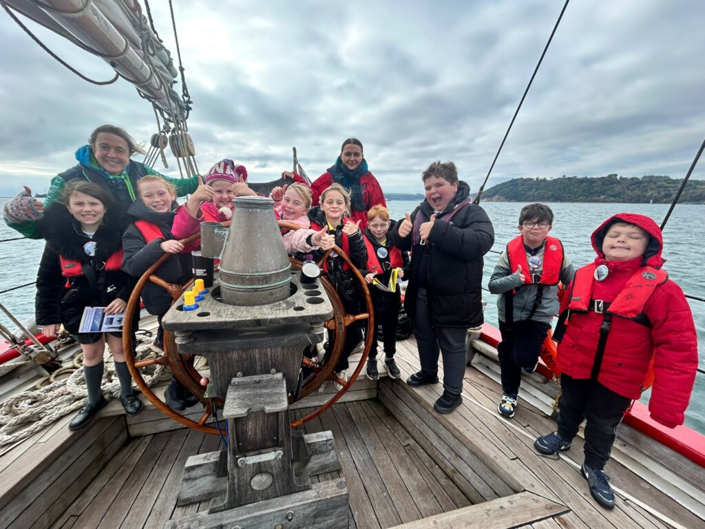 Marine Academy Pupils on a sailing boat, at the helm